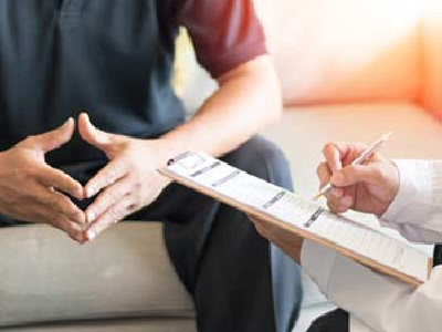 person with a clipboard talking to a seated person